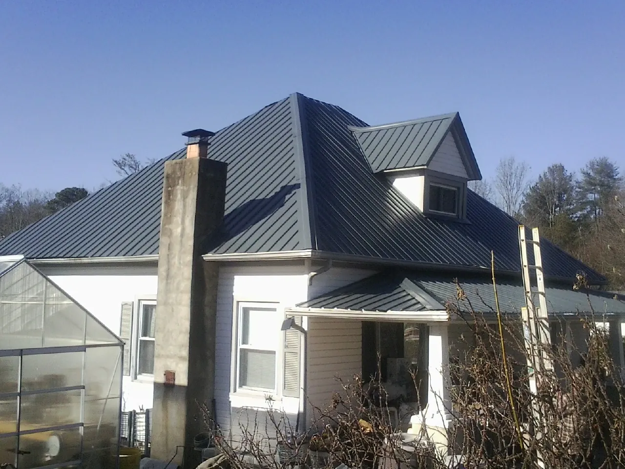 Dark blue standing seam metal roof on a white farmhouse with dormer — Slate & Tile Roof Repair by Roofing Brothers in Pierceton