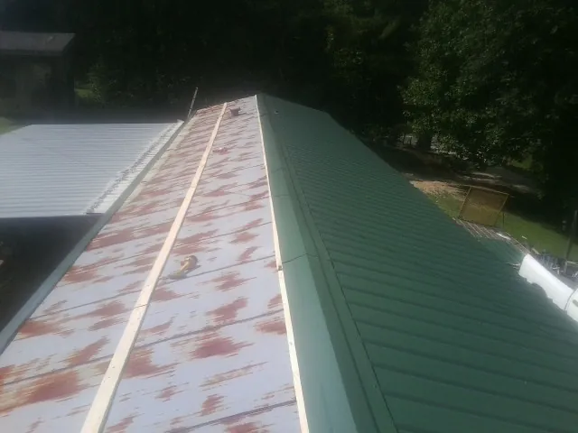 Old rusted panels beside newly installed green metal roofing — Wind Damage Roof Repair by Roofing Brothers in Pierceton