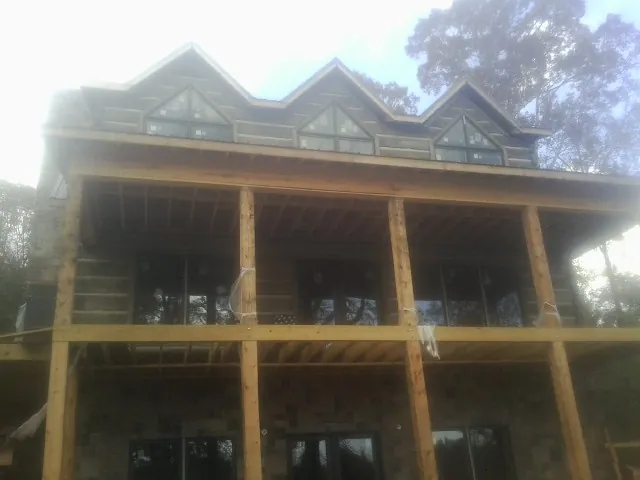 Dormers and porch framing on a large log home under construction — Roof Coating work by our crew in Pierceton