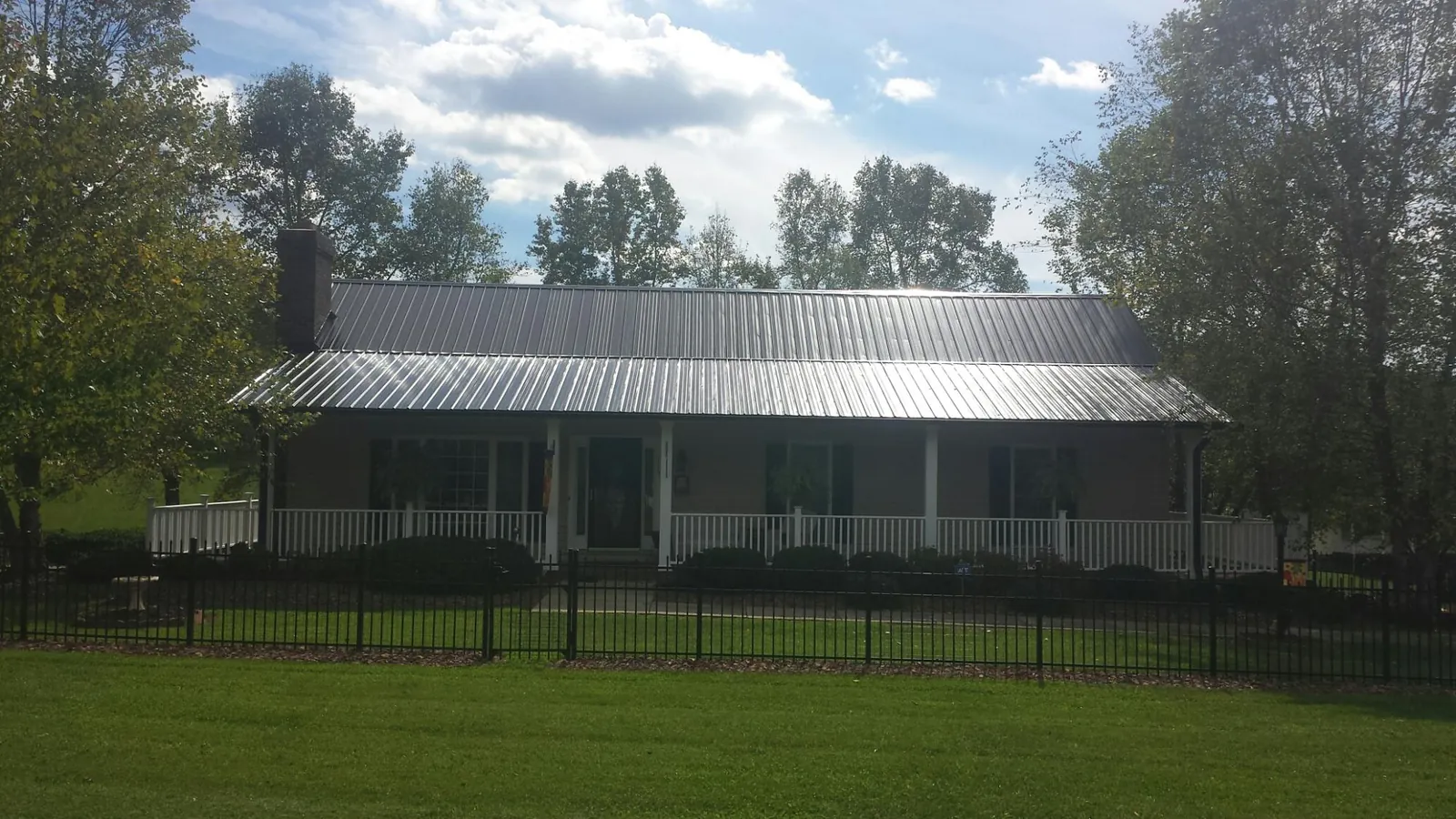 Gray metal roof on a brick ranch with a full width front porch — Gutter Guard Installation work by our crew in Pierceton