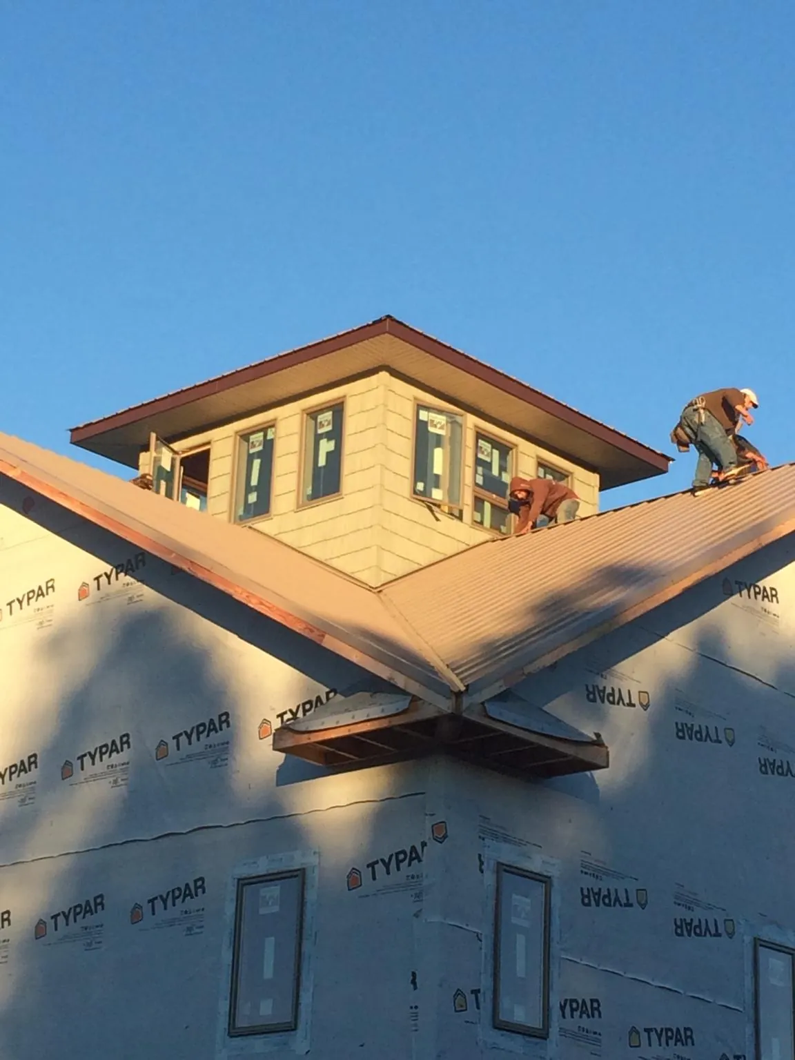 Roofers working around a rooftop cupola on a new metal roof at sunset — Roof Waterproofing in Pierceton by Roofing Brothers